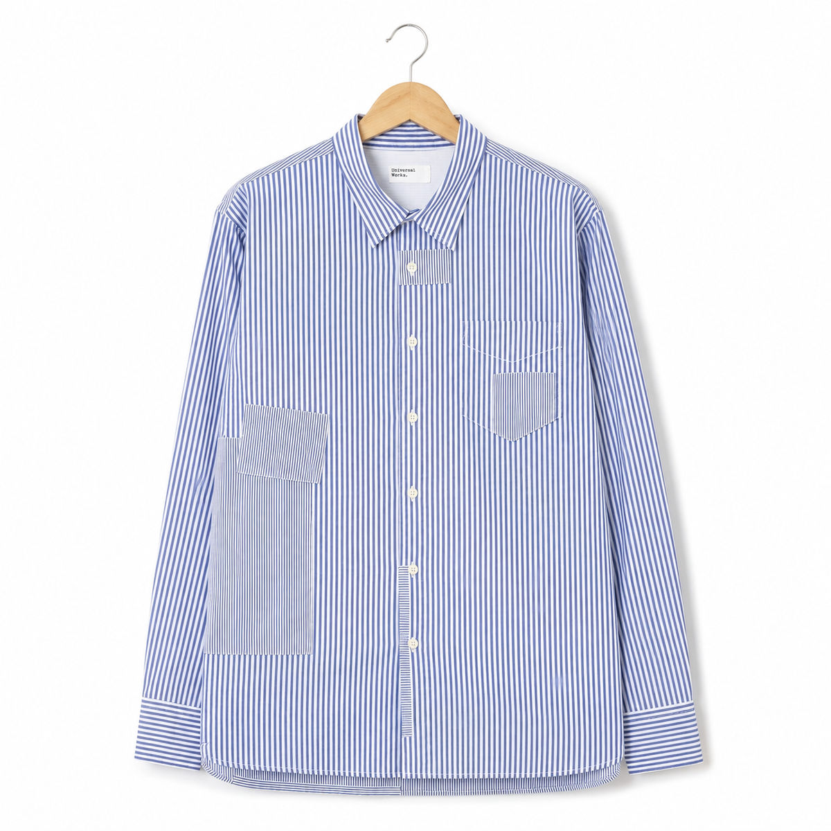 A long-sleeve button-up shirt with blue and white vertical stripes, featuring solid blue contrast pockets on the front, displayed on a wooden hanger against a clean white background.